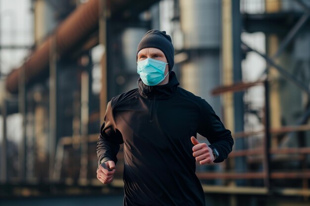 Foto corredor con máscara facial en un telón de fondo industrial