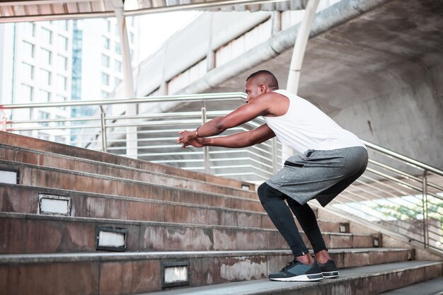 Corredor masculino afro-americano treinando nas escadas do estádio. Jovem exercício ao ar livre.