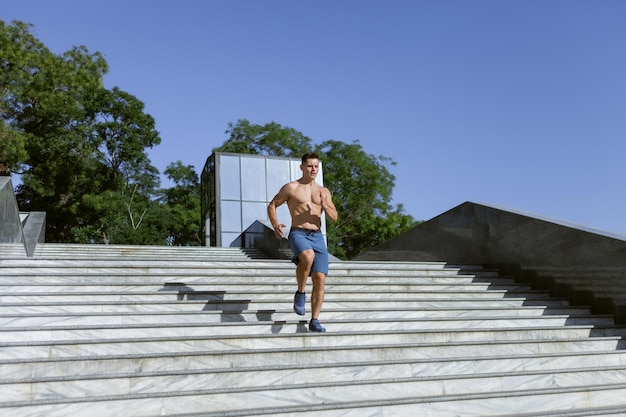 Corredor masculino apto jovem correndo escadas ao ar livre. Treino cardio. Estilo de vida saudável