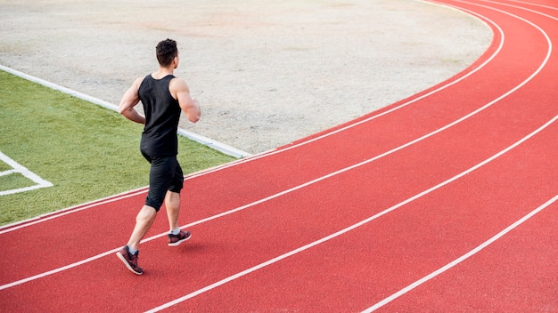 Corredor masculino corriendo en pista roja