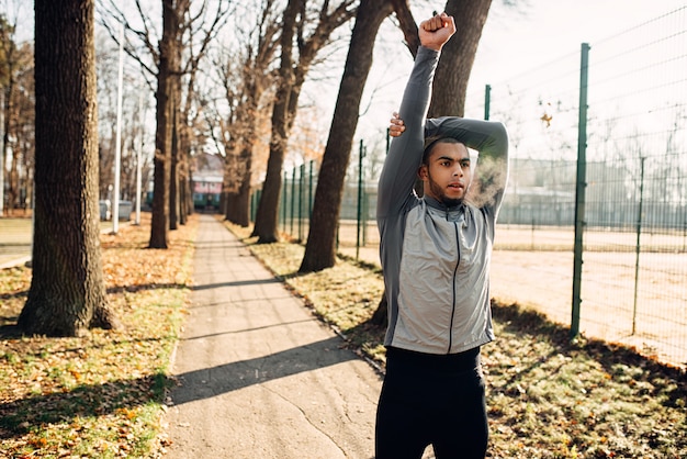 Corredor masculino fazendo exercícios de fitness no parque outono