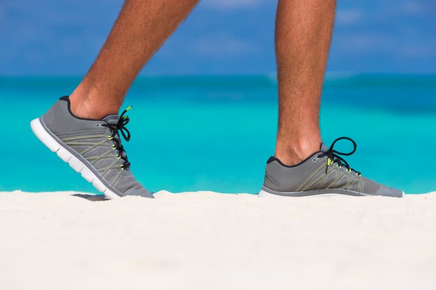 Corredor masculino joven que se prepara para comenzar en la playa blanca