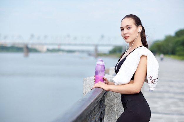 Corredor de la mujer asiática sana de la aptitud que se relaja después de correr al aire libre disfrutando de la vista en el paseo marítimo