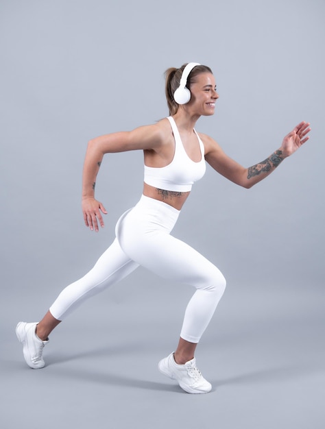 Corredor de mujer fitness Hermosa mujer deportiva alegre feliz fuerte posando sobre fondo aislado Mujer joven feliz en ropa deportiva sonriendo Modelo de fitness muscular