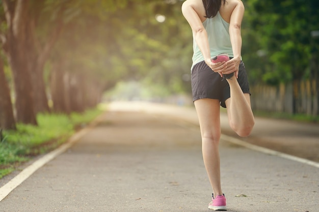 Corredor de mujer joven aptitud saludable estirando las piernas