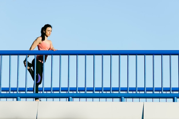 Corredor de mujer joven fitness estirando las piernas después de correr. Concepto de deporte.