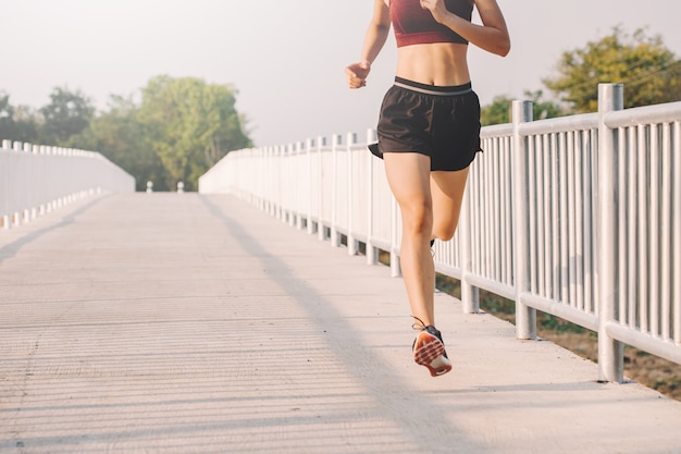 Corredor de la mujer joven que corre en el camino corriente en parque de la ciudad