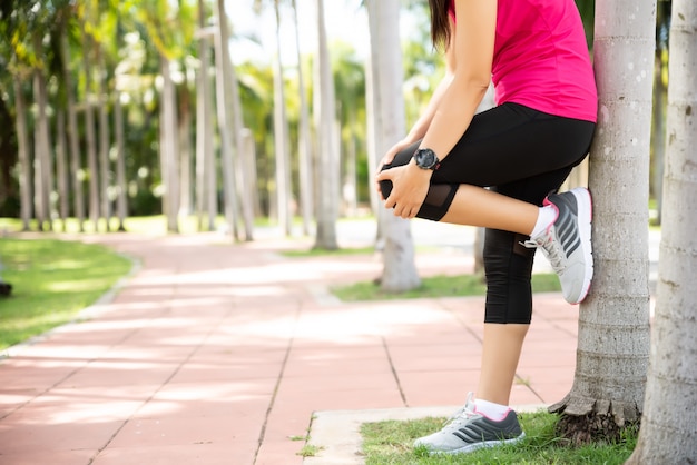 El corredor de la mujer siente dolor en su rodilla en el parque. Actividades de ejercicio