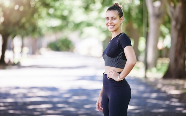 Corredor de retratos o mujer feliz lista para el ejercicio físico o el movimiento corporal mientras se relaja en el descanso Atleta deportiva cansada descansando o niña sana en entrenamiento con sonrisa o confianza en el parque