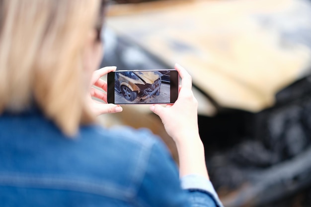 Corredor de seguros de mujer haciendo foto de coche quemado