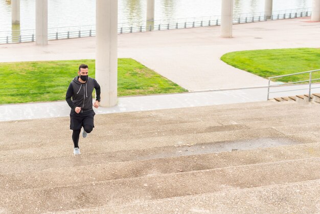 Corredor subiendo las escaleras. Vestida con ropa deportiva con una máscara.