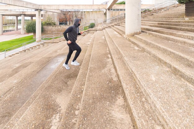 Corredor subiendo las escaleras. Vestida con ropa deportiva con una máscara.