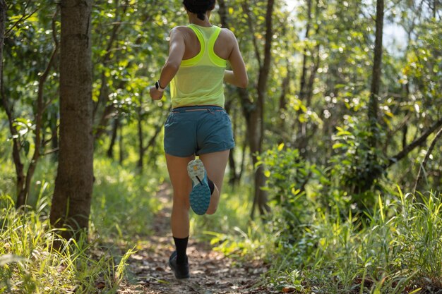 Corredora de fitness correndo em uma trilha florestal de verão