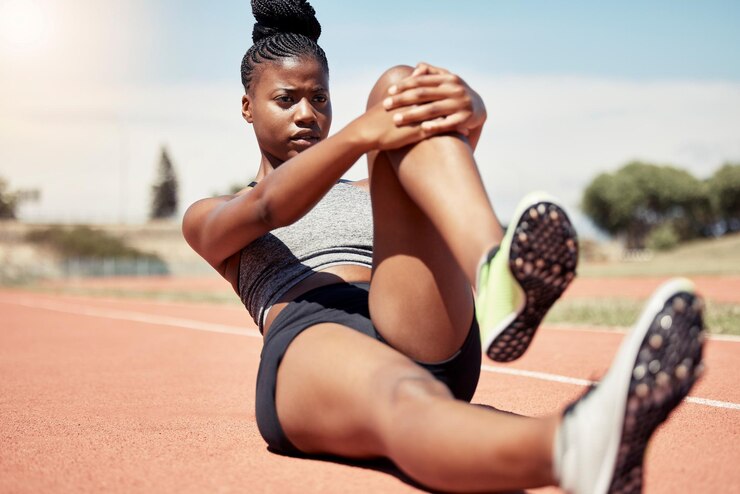 Foto corredora de mulher negra se alongando e treinando para corrida na pista de corrida no estádio com determinação e motivação de foco treino de fitness ao ar livre executando exercícios esportivos e trecho de atleta no chão