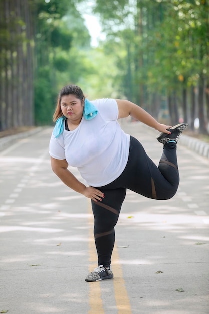 Corredora gorda estirando las piernas en la carretera