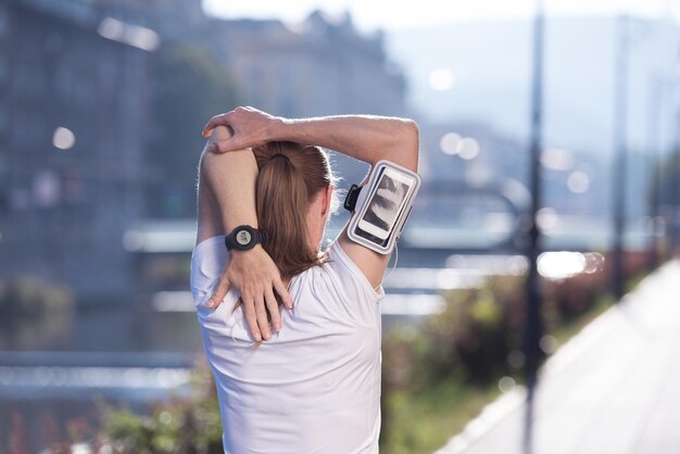 Corredora rubia en forma calentando y estirando antes de trotar por la mañana