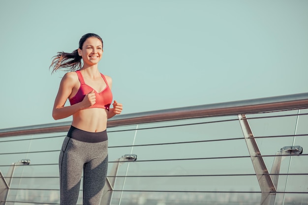 Corredora sonriente entrenando al aire libre en la ciudad