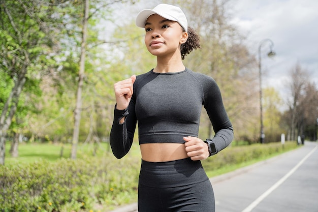 Una corredora usa un reloj de fitness para entrenar a un entrenador de carrera vestido con un chándal