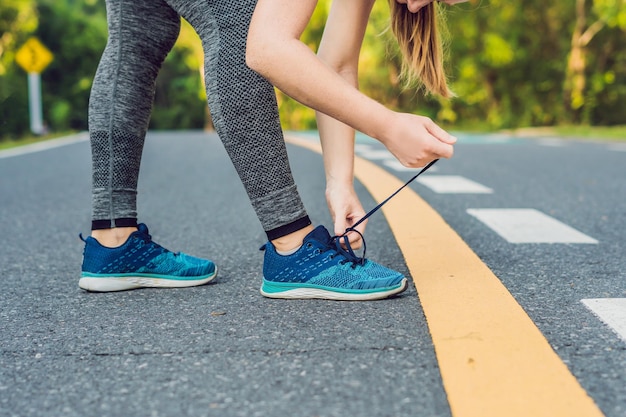 Corredoras atar sus zapatos preparándose para trotar fuera joven corredor girld preparándose para