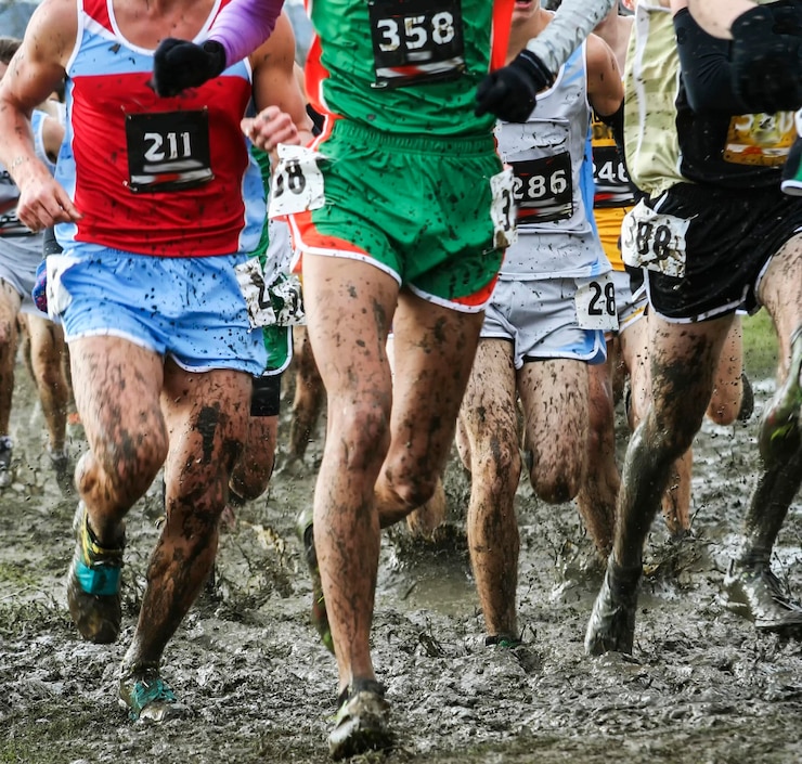 Foto corredores correndo um campeonato de ensino médio 5k em lama pesada com seus picos colados com fita adesiva