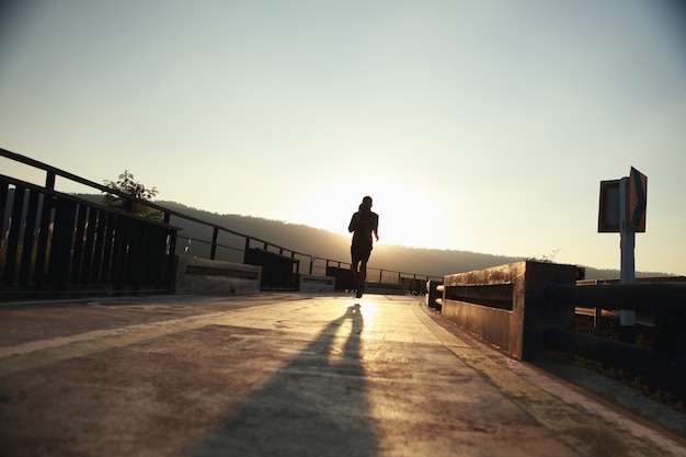 Los corredores jóvenes corren en la pista durante las horas de la tarde. Conceptos saludables para trotar (silueta)