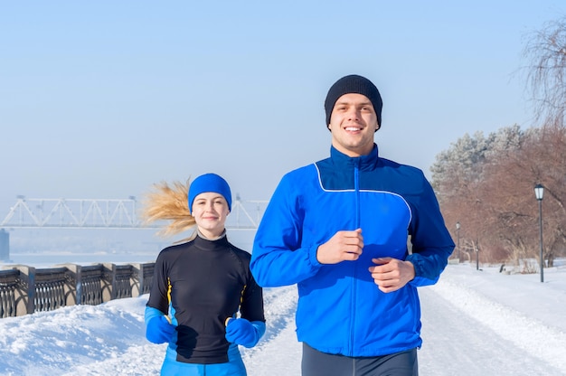 Corredores. Jóvenes parejas corriendo. Sport hombre y mujer trotar en terraplén de invierno