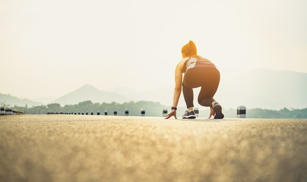 Los corredores de mujer en las zapatillas de carretera están preparados para abandonar el punto de partida.