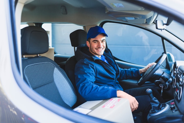 Correio alegre no carro sorrindo para a câmera