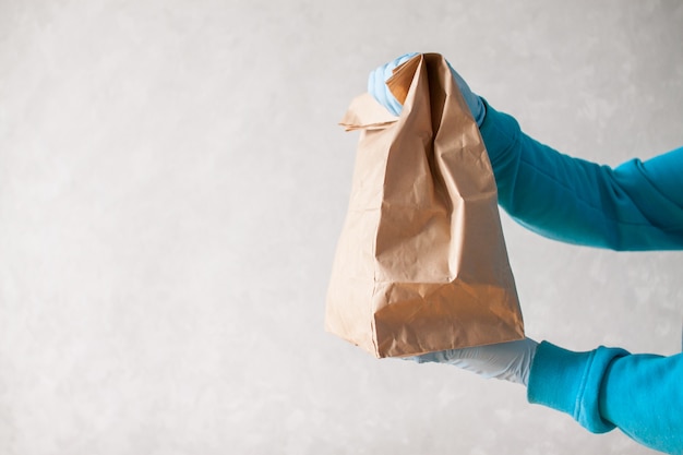 Correio de entrega de comida está segurando um grande saco de papel nas mãos
