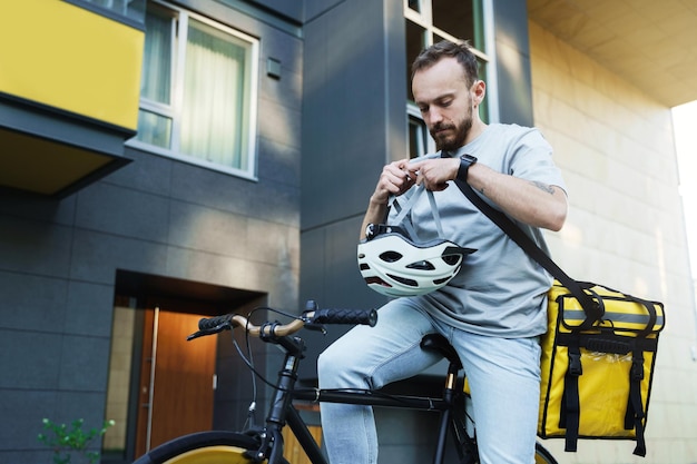 Correio de entrega expressa em bicicleta coloca capacete