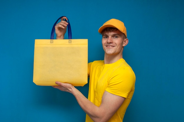 Correio de uniforme amarelo segura uma sacola ecológica de tecido e sorri para um entregador