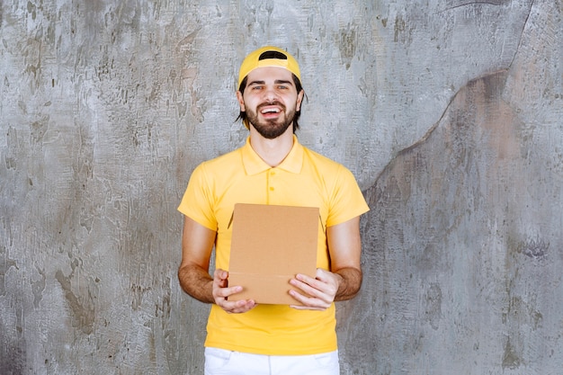 Correio de uniforme amarelo segurando uma caixa de papelão aberta