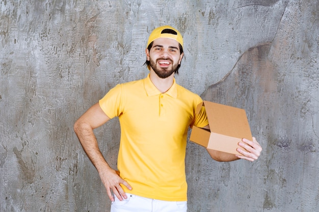 Correio de uniforme amarelo segurando uma caixa de papelão aberta