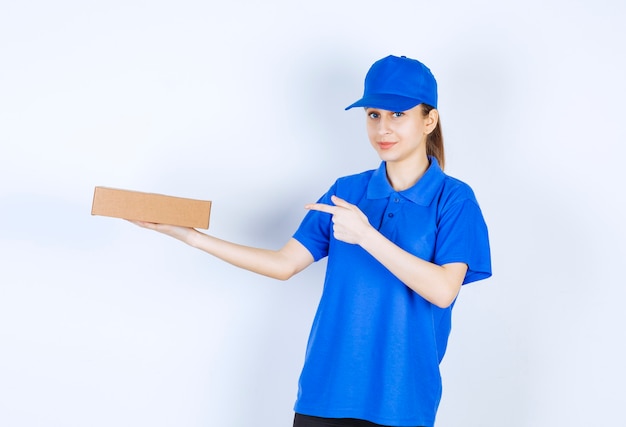 Correio feminino de uniforme azul, segurando uma caixa de papelão.