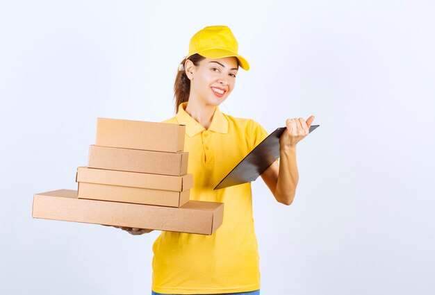 Correio feminino entregando um estoque de caixas de papelão e verificando a lista de clientes e endereços.