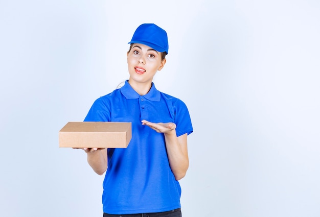 Correio feminino jovem em uniforme azul com caixa de papelão, segurando o espaço aberto.