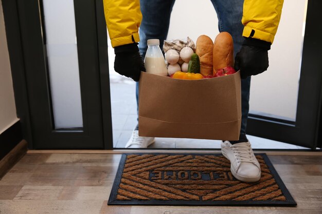Foto correio traz sacola de papel com comida para porta fechada serviço de entrega durante a quarentena devido ao surto de covid19