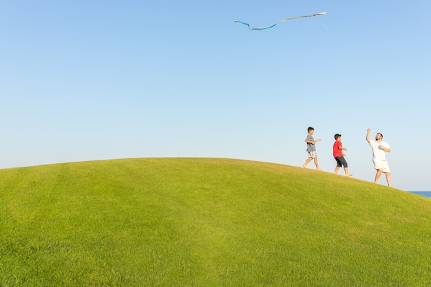 Correndo com pipa nas férias de verão, prado perfeito e céu à beira-mar