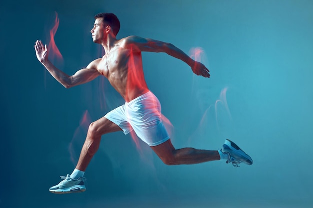Correndo homem atlético com torso nu no ar sobre fundo azul em neon light motion blur moderno