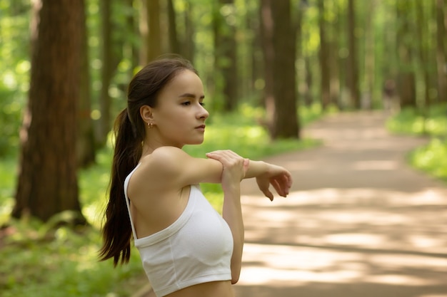 Correr, hacer deporte, mantenerse en forma. Chica hace ejercicios en el parque, hace ejercicios en la naturaleza