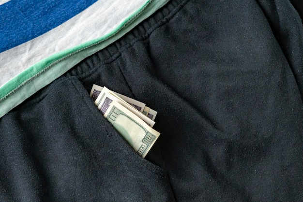 Una correspondencia de dinero en efectivo en dólares de cerca en los ingresos de los pantalones