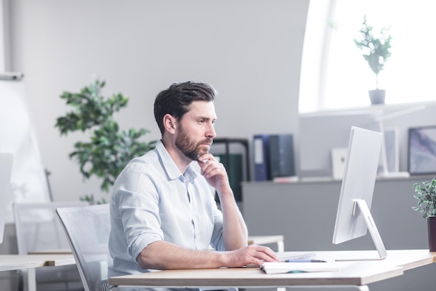 Corretor de ações de homem de negócios confiante sentado em frente à tela do monitor no escritório analisando estatísticas de dados de gráficos de índice analisa tendência de mercado agente de trabalhador de agência de negociação forex revisando o crescimento dos lucros