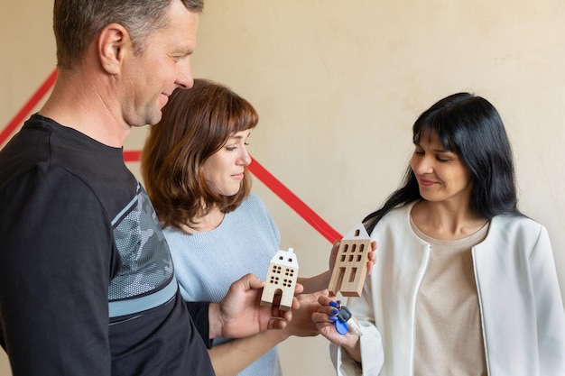 Foto corretor de imóveis entregando as chaves do novo apartamento para o jovem casal emocional conceito de novas casas, novo começo