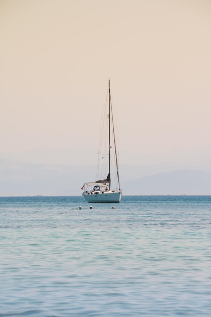 Corrida de iates à vela Yachting SailingLonely yacht com vela branca em mar aberto ao pôr do sol Barco solitário Bl