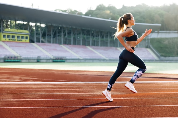 Corrida de velocistas feminina na arena de pista ao ar livre. Corredora de maratona feminina na arena esportiva profissional