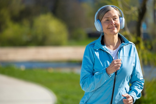 Foto corrida matinal mulher sorridente de casaco azul a correr no parque