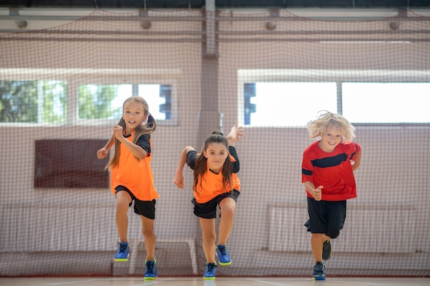 Corriendo. Niños en ropa deportiva brillante corriendo en el gimnasio.