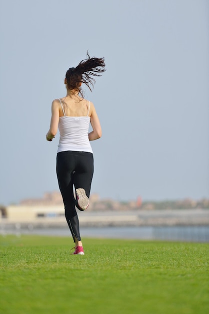 Corriendo en el parque de la ciudad. Mujer corredor fuera de jogging por la mañana con la escena urbana de Dubai en segundo plano.