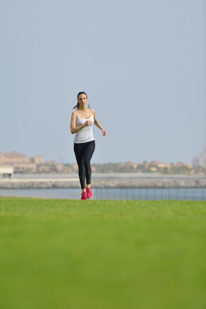 Corriendo en el parque de la ciudad. Mujer corredor fuera de jogging por la mañana con la escena urbana de Dubai en segundo plano.