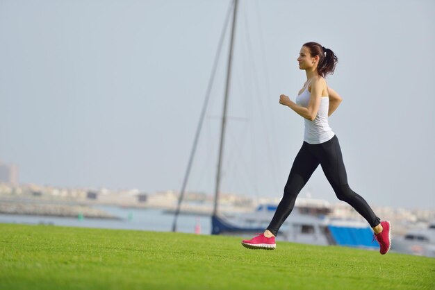 Corriendo en el parque de la ciudad. Mujer corredor fuera de jogging por la mañana con la escena urbana de Dubai en segundo plano.